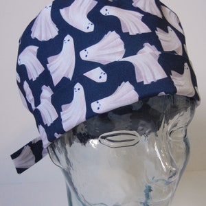 May include: A blue scrub hat with a white ghost pattern. The hat has a tie on the side.