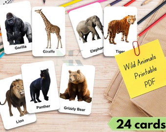 May include: Set of flashcards featuring various wild animals, including a gorilla, giraffe, elephant, tiger, lion, panther, and grizzly bear. Each card displays an animal image with its name. A yellow sticky note reads "Wild Animals Printable PDF". The set includes 24 cards.
