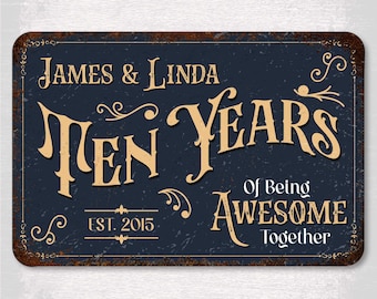 May include: A rectangular metal sign with a dark blue background and a distressed, rusty brown border. The sign reads "James & Linda Ten Years Of Being Awesome Together Est. 2015" in a vintage font.