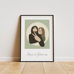 May include: A framed illustration of a couple, a man and a woman, in a circle on a green background. The man is wearing a black hoodie and has a beard. The woman is wearing glasses and a green shirt. The text "Clara & Johannes" is below the illustration.