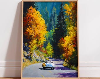 May include: A framed art print depicting a silver convertible car driving on a winding road through a forest. The scene features vibrant yellow and orange autumn foliage on the trees, contrasting with deep green pines and a gray asphalt road.