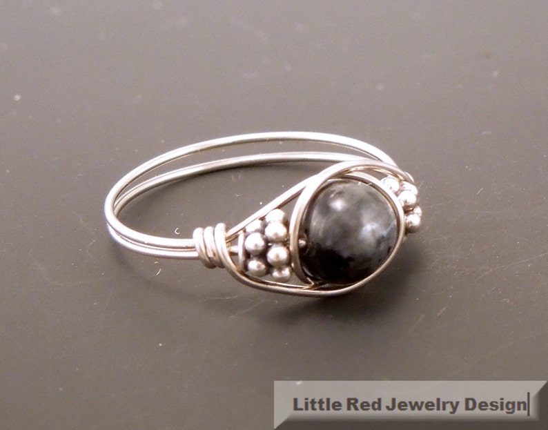 May include: A silver ring with a black gemstone and silver beads. The ring is made of wire and has a simple design.