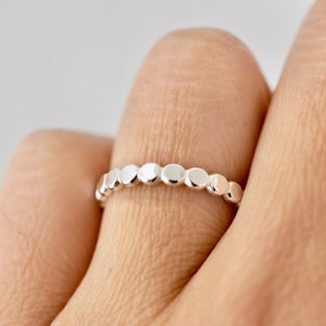 May include: A silver ring with a row of small, round, raised beads.