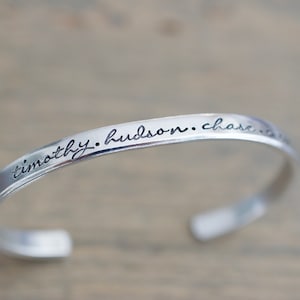 May include: Silver bangle bracelet with the inscription "timothy. hudson. chase. the. stars."
