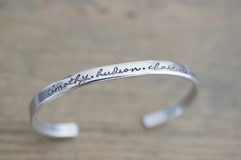 May include: Silver bangle bracelet with the inscription "timothy. hudson. chase. the. stars."