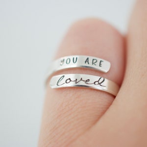May include: A silver ring with the words "You are loved" engraved on it.
