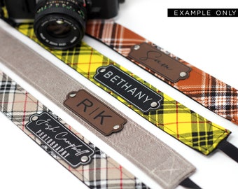 May include: Four camera straps with different plaid patterns and personalized leather name tags. The name tags read "Bethany", "Rik", "Josh Campbell Photography", and "Sarah".