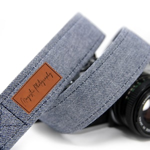May include: A blue and white herringbone camera strap with a brown leather patch that says "Majestic Photography".