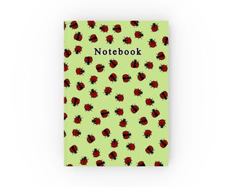 May include: A green notebook with a ladybug pattern and the word "Notebook" printed on the front cover.