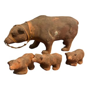 May include: A set of four brown bear figurines. The largest bear has a leather collar and is standing. Three smaller bears are positioned below. The figurines appear to be made of a clay-like material.