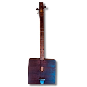 May include: A handmade, wooden cigar box guitar with a dark brown body and a long neck. The body is rectangular with a sound hole and a blue accent on the bottom. The guitar has strings and tuning pegs.