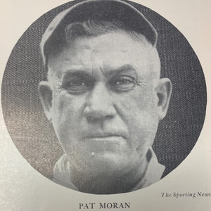 May include: Black and white photo of a man wearing a baseball cap. The photo is in a circle with the text "The Sporting News" and "PAT MORAN" below the circle.