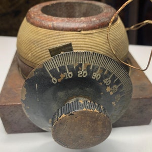 May include: A vintage wooden base with a black dial and a wooden knob. The dial has numbers from 0 to 50. The base is made of wood and has a brown finish.