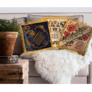May include: Three vintage silk banners with gold fringe. One is navy blue with gold lettering and floral accents, another is cream with a National Guard emblem, and the third is cream with red roses and the text "Camp Beale Calif."