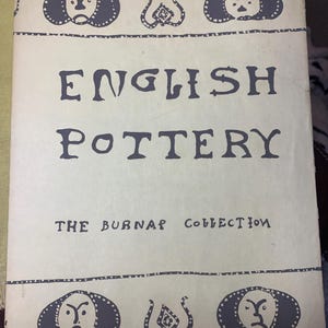 May include: A vintage book cover titled "ENGLISH POTTERY" with "THE BURNAP COLLECTION" text. The cover is cream-colored with dark blue illustrations of faces and abstract designs.