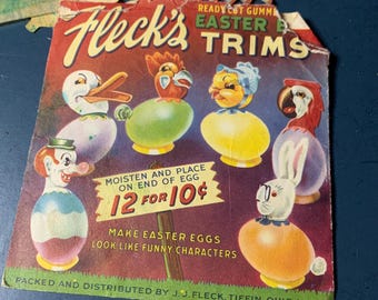 Könnte beinhalten: Eine Vintage-Packung mit Fleck's Osterei-Verzierungen, mit einer bunten Auswahl an vorgefertigten gummierten Figuren. Die Packung enthält 12 Verzierungen für 10 Cent und Anweisungen, sie anzufeuchten und auf das Ende eines Eies zu legen, um es wie eine lustige Figur aussehen zu lassen.