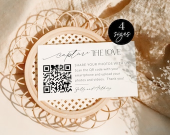 May include: A white card with black text that says "Capture the Love" and has a QR code. The text also says "Share your photos with us. Scan the QR code with your smartphone and upload your photos and videos. Thank you!" The card is sitting on a woven wicker tray. The text "Sally and Anthony" is written below the QR code. The text "Love Story Paperie" is at the bottom of the image.