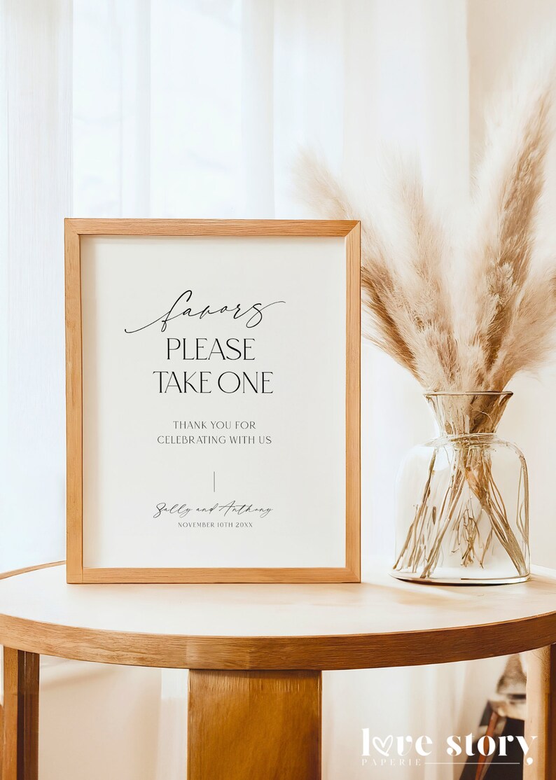 Op de afbeelding: Een ingelijst bord met de tekst "favors please take one" en "Thank you for celebrating with us", gevolgd door de namen "Sally and Anthony" en de datum "November 10th 20XX".