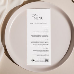 May include: A white card with black text on a white plate. The card has the words "The Menu" at the top, followed by "Sally & Anthony | 12.12.20XX". The menu includes starters, main courses, and desserts. There is a QR code at the bottom of the card that says "Share the Love" and asks guests to share photos and videos.