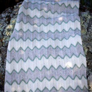 May include: A white and grey chevron patterned knitted blanket with a green and white chevron pattern.