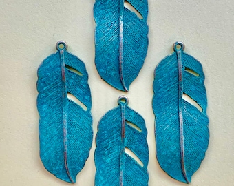 May include: Four teal blue metal feather charms with a cutout design. The feathers have a distressed finish.