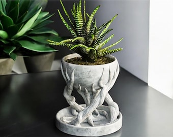 May include: A grey ceramic planter shaped like a set of tree roots with a round pot on top. The planter is holding a green succulent plant.