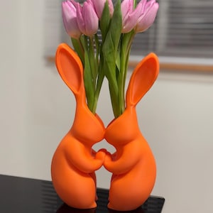 Puede incluir: Dos jarrones de cer&aacute;mica de conejo naranja que sostienen un ramo de tulipanes rosas.