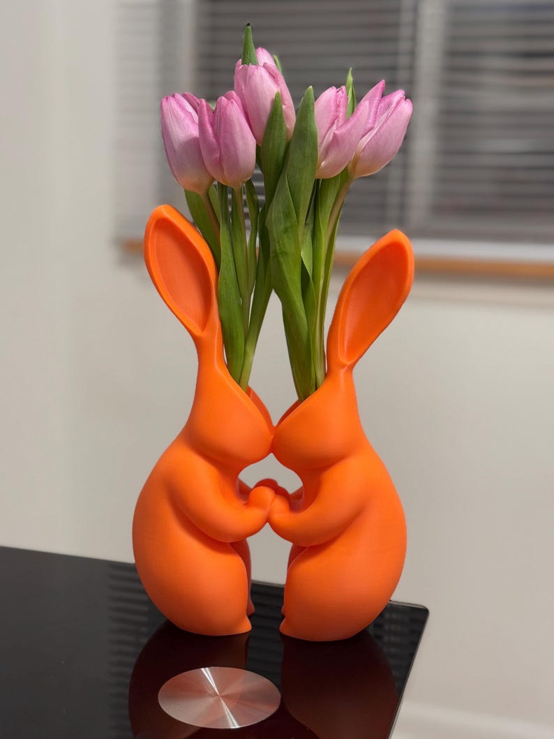 Puede incluir: Dos jarrones de cer&aacute;mica de conejo naranja que sostienen un ramo de tulipanes rosas.