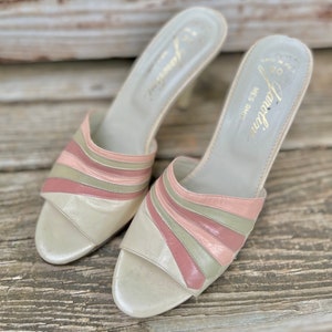May include: A pair of white leather heeled sandals with pink and green striped detailing. The sandals are open-toed and have a low heel. The brand name "Fontana" is printed on the insole.