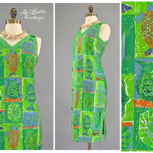 Puede incluir: Un vestido verde sin mangas con escote en V y un estampado colorido de peces y conchas. El vestido tiene una abertura lateral y está hecho de una tela ligera. La Belle Vintage está impreso en la parte superior de la imagen.