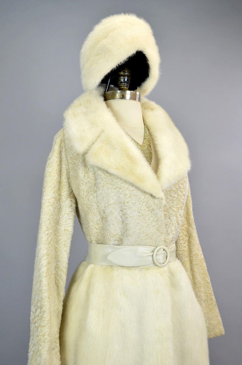 May include: A white fur coat with a matching fur hat and a white leather belt with a silver buckle.
