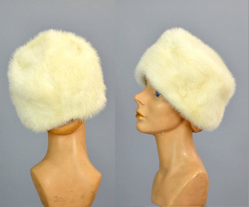 May include: A white fur hat with a wide brim. The hat is made of soft, fluffy fur and has a simple, elegant design.