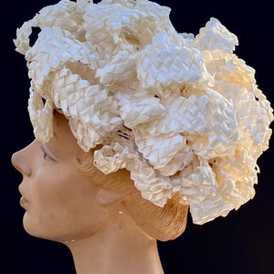May include: A white woven hat with a large, voluminous design. The hat is made of a soft, pliable material and has a delicate, feminine look.