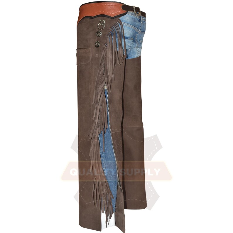 May include: Brown leather chaps with fringe and a zip. The chaps have decorative metal buttons and a brown leather belt. The top section is a lighter brown. The chaps are worn over blue jeans.