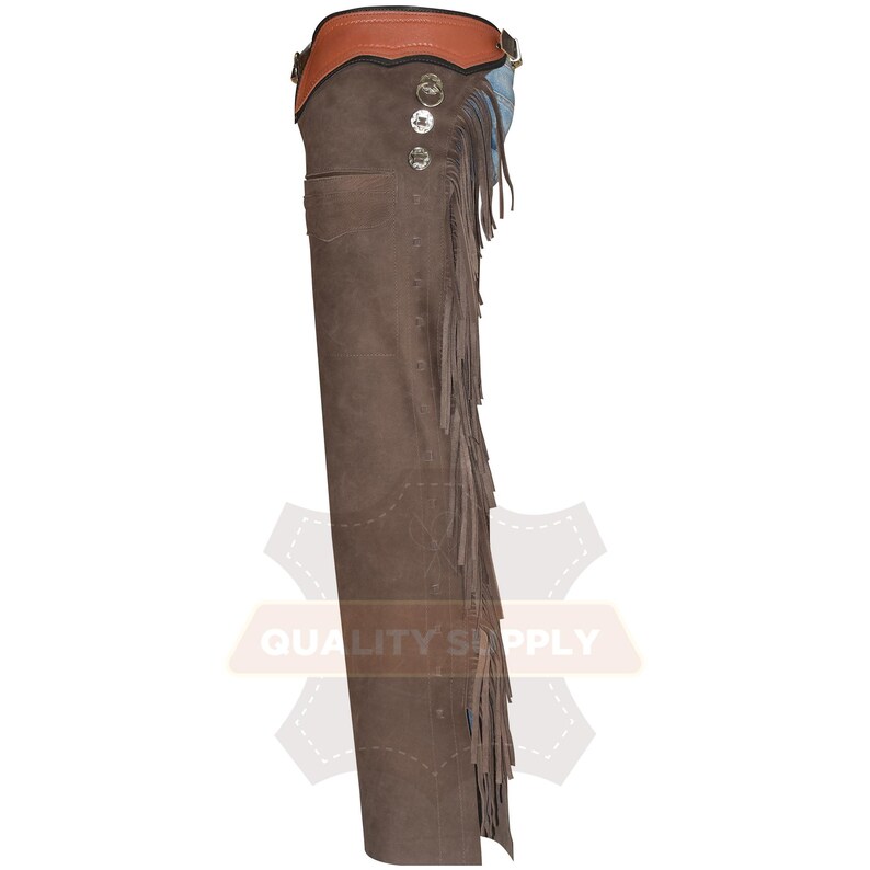 May include: Brown leather chaps with fringe detailing. The chaps feature a brown suede-like texture, a brown leather belt, and blue accents. Silver-coloured buttons and rivets add a decorative touch to the western-style garment.