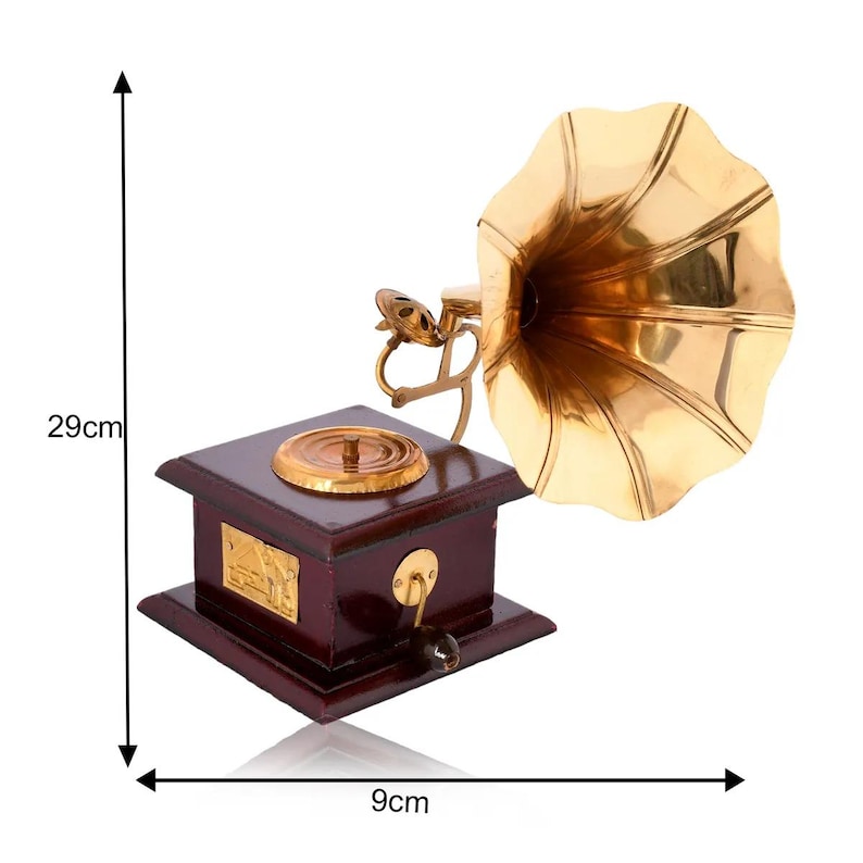 May include: A vintage-style gramophone with a polished brass horn and a dark wood base. The gramophone is 29 cm tall and 9 cm wide. It features a crank handle and a decorative brass plate on the front. The horn is a bright gold color.