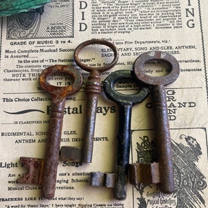 May include: Three antique keys with tarnished metal finishes. The keys are arranged on a vintage sheet of music with text about the "National Singer" and "Festal Days".