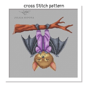 Op de afbeelding: Kruissteekpatroon met een cartoonvleermuis die ondersteboven aan een bruine tak hangt. De vleermuis heeft een bruin lichaam, een paarse jumpsuit en donkergrijze vleugels. De tekst "cross Stitch pattern" en "JULIJA SUPOVA" zijn zichtbaar.