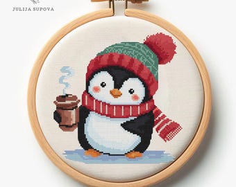 May include: A cross-stitch pattern of a penguin wearing a red and green hat and scarf, holding a cup of coffee. The penguin is standing on a blue background.