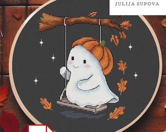 Op de afbeelding: Een kruissteek borduurring met een vriendelijk spookje met een pompoenhoed, schommelend aan een tak. Het ontwerp bevat herfstbladeren en sterren op een donkergrijze achtergrond. De tekst "JULIJA SUPOVA" is zichtbaar.