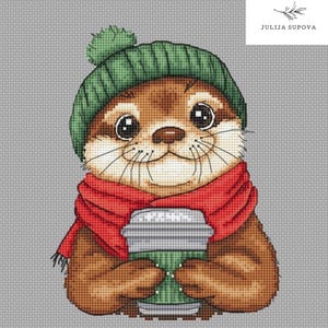 Puede incluir: Una nutria marrón y tostada que lleva un gorro de punto verde con un pompón blanco y una bufanda roja, sosteniendo una taza para llevar verde y blanca.
