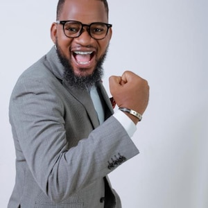 Pode incluir: Um homem de terno cinza, camisa branca e óculos pretos sorri e fecha o punho. A imagem tem o texto "100 Software Developer Mindset Questions. (With Answers)" no topo e "Author: Stephen Webb" na parte inferior.