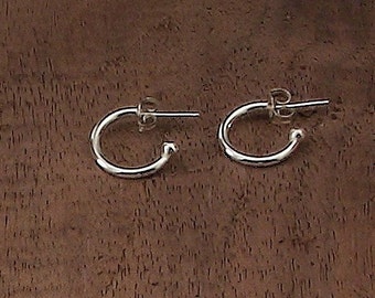 May include: A pair of silver hoop earrings. The earrings are small and simple, with a smooth finish.