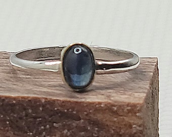 May include: A silver ring with a dark blue oval gemstone.