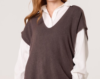 May include: A brown V-neck sweater vest over a white collared shirt and black leggings. The sleeveless sweater has a ribbed hem and a relaxed fit. The outfit is simple and stylish.