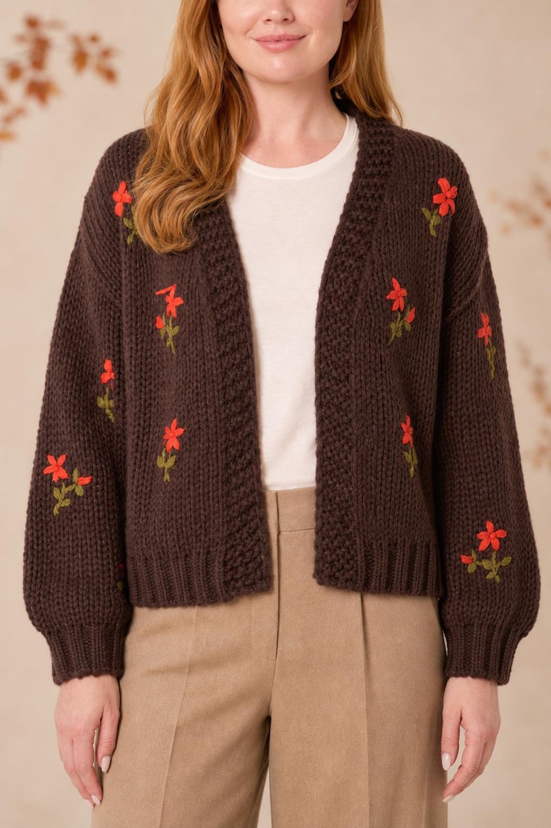 May include: A dark brown open-front knit cardigan featuring long sleeves and a ribbed trim along the collar and cuffs. The garment is decorated with small, embroidered red flowers with green stems scattered across the front and sleeves.