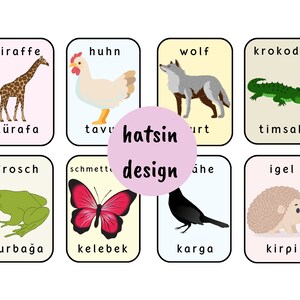May include: Eight colorful flashcards with images of animals and their names in German and Turkish. The animals include a giraffe, chicken, wolf, crocodile, frog, butterfly, crow, and hedgehog.