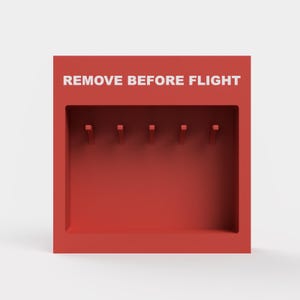 May include: Red plastic box with the text "REMOVE BEFORE FLIGHT" in white letters. The box has five slots for holding items.