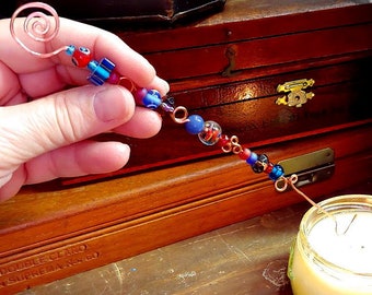 hammered copper candle snuffer handmade magickal wand suncatcher evil eye talisman in red and purple and blue glass beads Christmas ornament