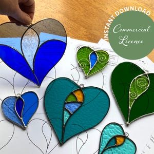May include: Several stained glass heart decorations in shades of blue, green, and teal, with silver-coloured metal edging. The image includes the text "Instant Download Commercial Licence".